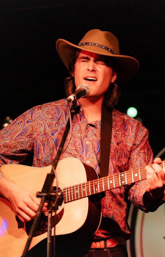 Luke Moore singing with acoustic guitar and cowboy hat