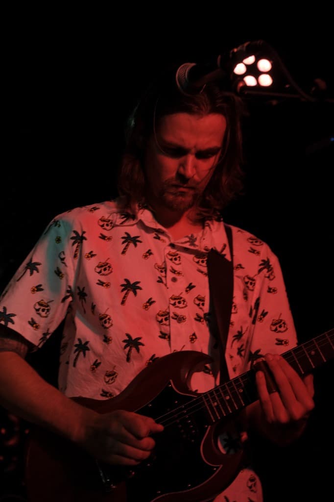 Luke Moore performing with Gibson guitar under stage lights