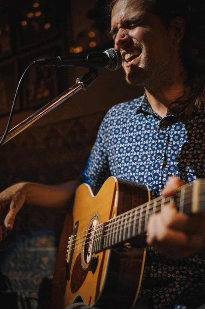 Luke Moore passionately singing with acoustic guitar close-up